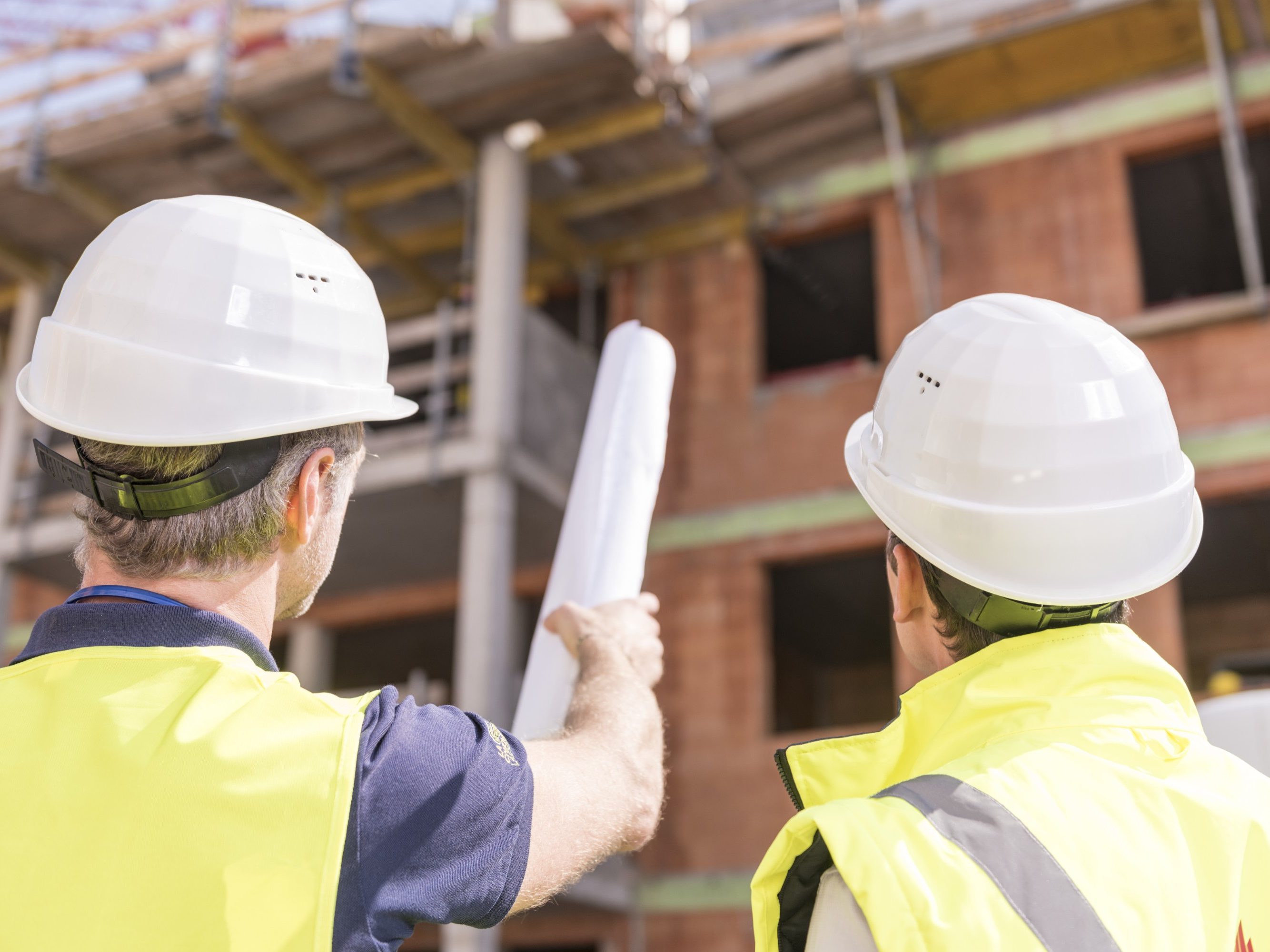 Builder pointing at building shell with blueprint